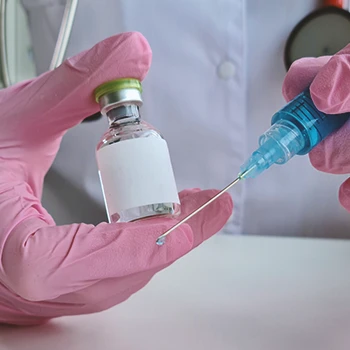 A doctor holding a bottle and syringe filled with testosterone cypionate