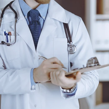 A doctor writing down the Testosterone Cypionate drug interactions on a clipboard