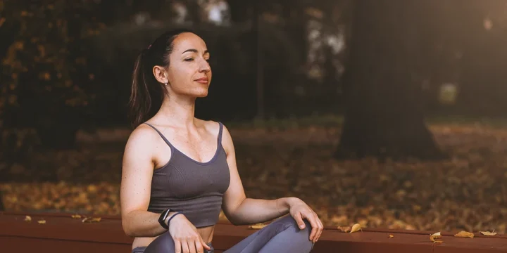 A fit woman doing yoga at the park after taking in nootropics