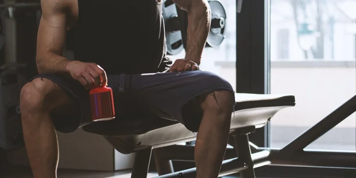 A buff male holding a nootropics bottle in a gym