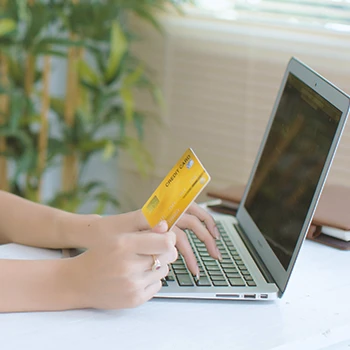 A woman holding a credit card in front of a laptop