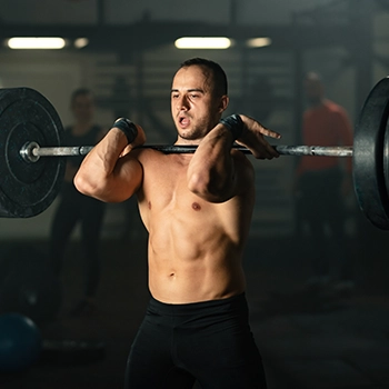 Holding barbell performing hang cleans