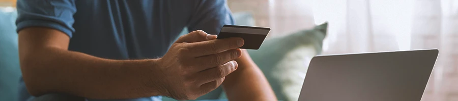 A person holding a credit card in front of a computer