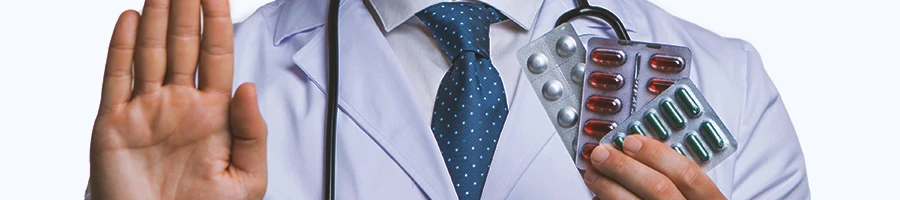 A doctor holding supplements while signing stop with their hands