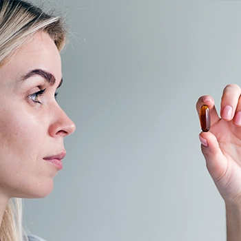 Woman staring at a single supplement pill