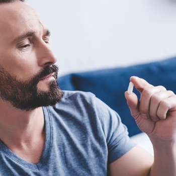 Bearded person staring at a pill