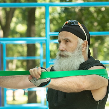 Old bearded person holding resistance band for workouts