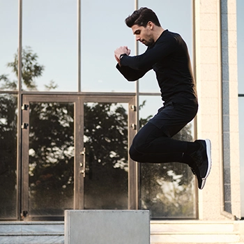 A man doing a standing long jump outside his home