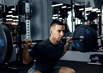 A guy in the gym doing barbell squats