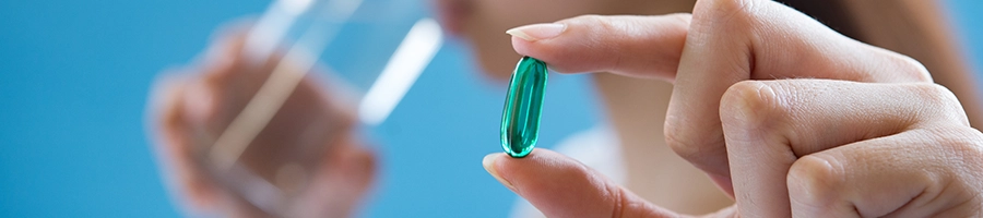 Woman drinking plenty of water while holding nootropics pill