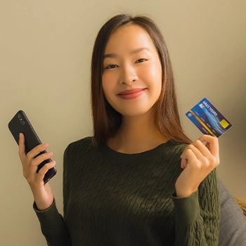 Holding phone and bank card to show how where to buy online