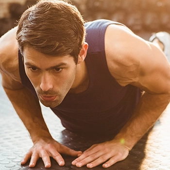 A man doing compound triceps exercises with diamond push-ups indoors