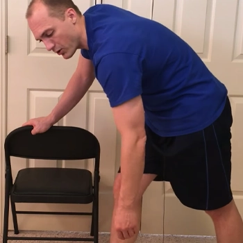 Holding on a chair doing pendulum exercise