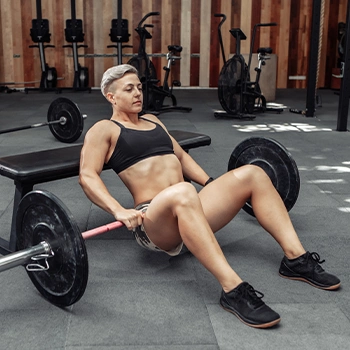 Woman holding barbell performing hip thrust