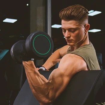 A buff male doing dumbbell preacher curls in the gym