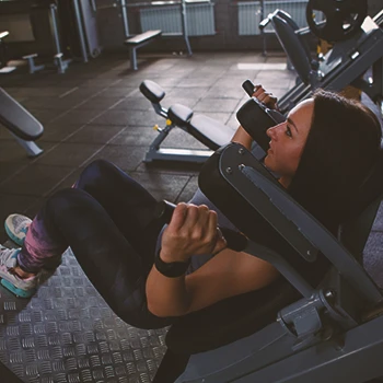 A woman doing a hack squat on a hack squat machine in the gym
