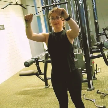 A person doing a high cable pulley lat extension in the gym