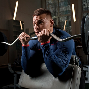 A woman doing preacher curls using EZ bar