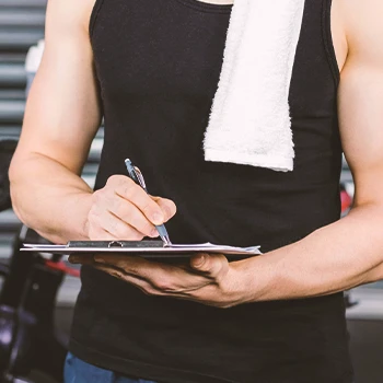 A gym instructor writing down on a clipboard