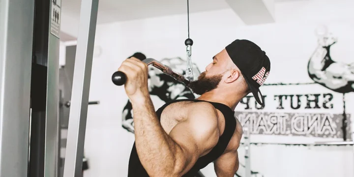 A man doing face pulls with a cable machine in the gym