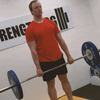 A buff male doing barbell shrugs