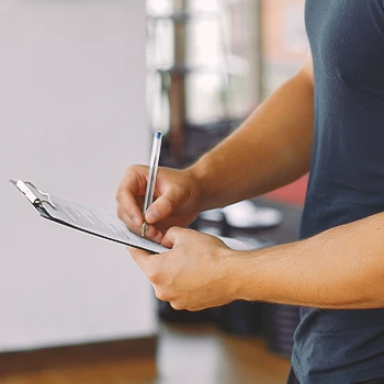 A gym coach explaining block periodization while writing on a clipboard