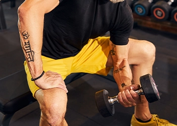 photo of a man doing Concentration curls in gym which is of Flex Lewis's arms workout