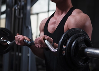 photo of a man doing bicep curls using the EZ bar