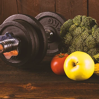 Close up shot of vegetables and a dumbbell