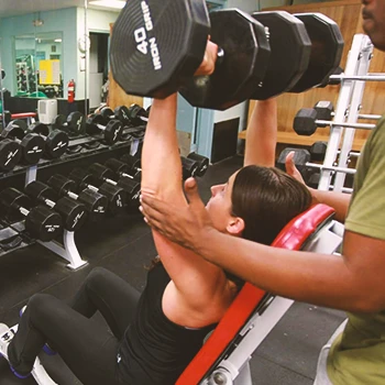 A gym coach helping a beginner lifter
