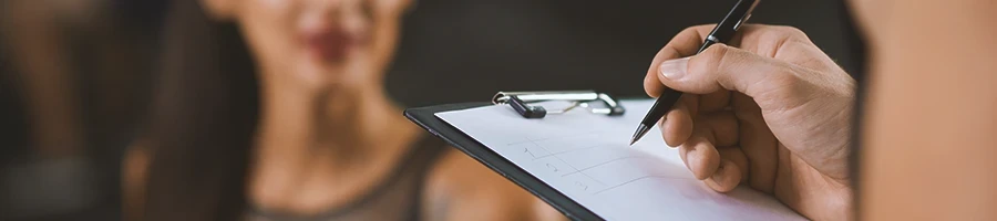 A gym coach writing down something on a clipboard