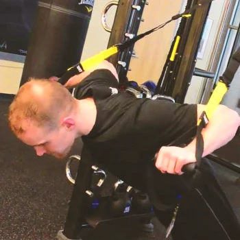 A buff male doing a suspension pushup workout