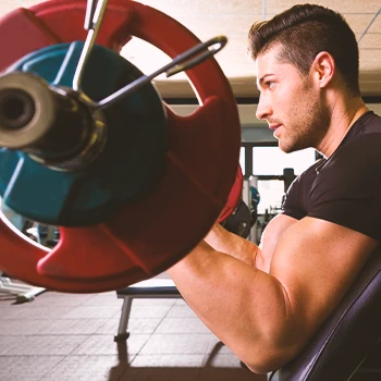 A person doing a preacher curl in the gym