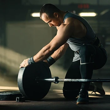 A man placing a weight plate on a barbell