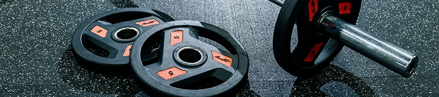 Barbell and weight plates on the floor of a home gym