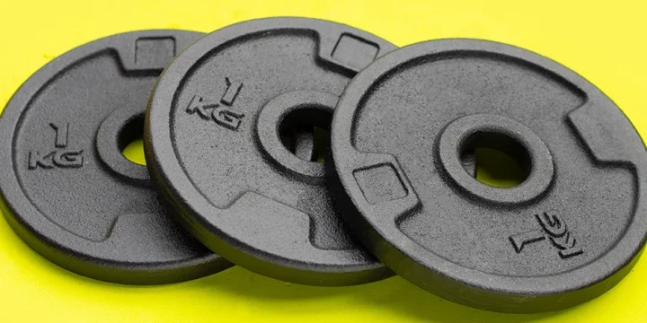 Weight plates on a yellow background that you can buy for your home gym