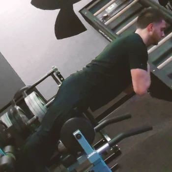 A person doing an isometric hold glute ham raise at a gym