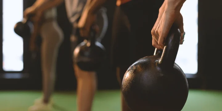 A row of people doing single kettlebell workouts in the gym