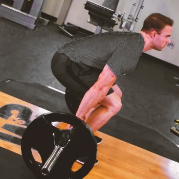 A person doing barbell hack squats at a gym