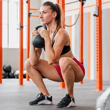 A woman doing goblet squats using a kettlebell