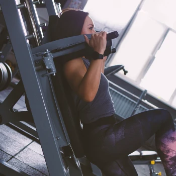 A person doing hack squats on a machine in the gym