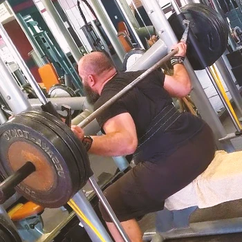 A person doing a box squat in the gym on a smith machine