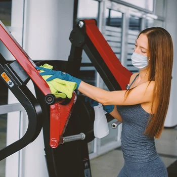 A person spraying lubricant on a weight machine