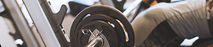 Close up shot of a person working out with a barbell at a home gym machine