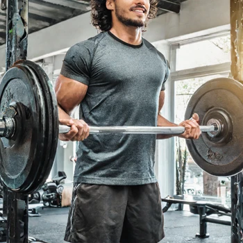 A guy in the gym using a barbell in his workout