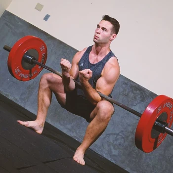 A person doing zercher squats with a barbell