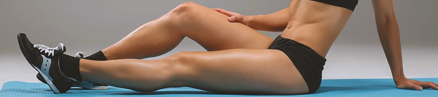 A woman stretching her thighs on a yoga mat