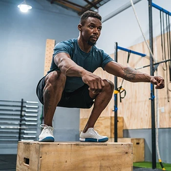 A man doing box jumps in the gym