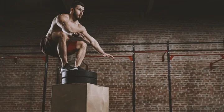 A person at the gym working out with box jumps