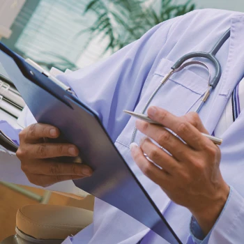 Close up shot of a doctor writing down on a clipboard